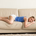 Frau in blauem Oberteil schläft auf einer beigen Couch Frau in blauem Oberteil schläft auf einer beigen Couch