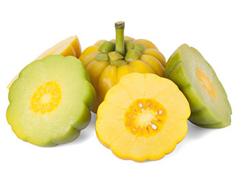 Eine ganze gelbe Garcinia Cambogia umgeben von aufgeschnittenen gelben und grünen Garcinia Früchten auf weißem Hintergrund