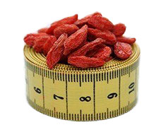 Gelbes eingerolltes Maßband auf dem getrocknete Goji Beeren liegen