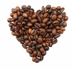 Ein kleines aus gerösteten Kaffeebohnen geformtes Herz auf weißem Hintergrund Ein kleines aus gerösteten Kaffeebohnen geformtes Herz auf weißem Hintergrund