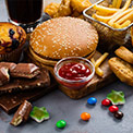 Süßigkeiten und Fast Food nebeneinander auf dunklem Untergrund
