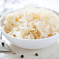 Eine weiße Keramikschüssel mit Sauerkraut auf hellem Untergrund