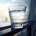 Glas mit Wasser und Eiswürfeln steht auf einem Fensterrahmen